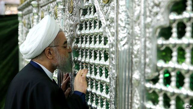 Iranian President Hassan Rohani kisses a religious shrine while visiting the holy city of Qom on February 25.