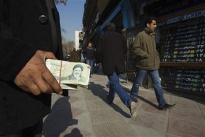 A money changer holds Iranian currency as he waits for customers in Tehran's business district